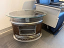 Accent table for reception areas with custom aluminum insert for magazines or books. made from tailpipe assembly of a convair aircraft. oval glass top. Burnished bronze patina with polished steel rings. 19.5" high